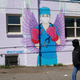 A man in a mask walks by a mural depicting a medical worker with a mask covering her mouth and nose, wearing boxing gloves and angel-like wings on her back on April 14, 2020, in downtown Denver.